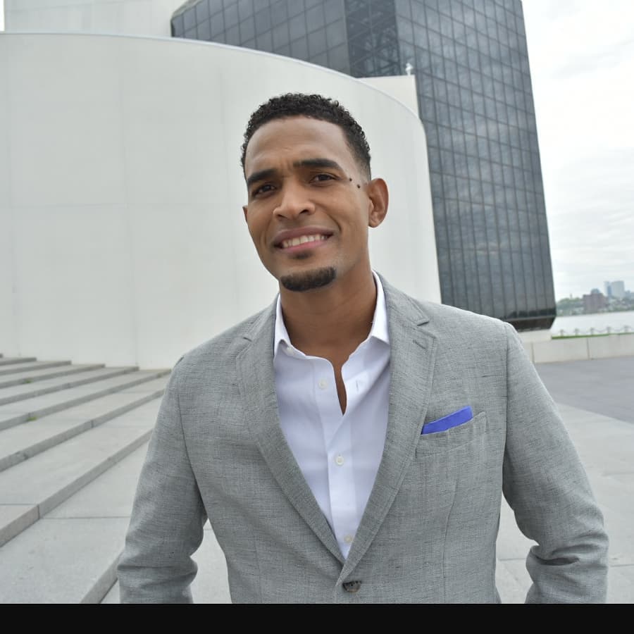 Retrato de Charlie Pe con traje gris frente a un edificio moderno (2018)